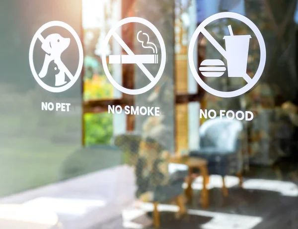 Close-up of no food and drink, pet and no smoking forbidden sign, white sticker on glass front door of cafe or restaurant.