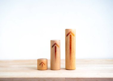 İşletme grafiği beyaz arka plandaki ahşap masaya izole edilmiş adımlar atarken tahta sopaların üzerinde yükselen oklar. İş büyümesi grafik süreci, hedef, başarı, kalkınma ve ekonomik iyileştirme kavramları.