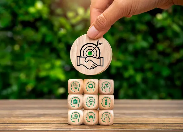 Green life society community members sustainability, environment responsibility, conserve resources concept. Cooperation icon block in hand put on wood cubes stack with human, renewable energy symbol.