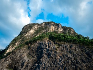 Zirvenin zirvesi kaya dağ dokusu arkaplanı, aşağıdan manzara. Mavi gökyüzünde güçlü bir uçurum ve bulutlu arka planlar, doğa yolculuğu manzarası. Tayland 'ın Phang Nga eyaletinde eski bir taş ocağı..