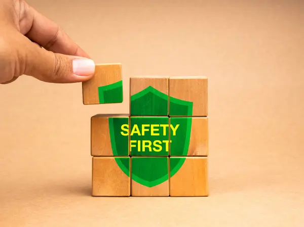 Safety first concept. Hand holding a last piece, put on the wooden cube block puzzle stack with text \