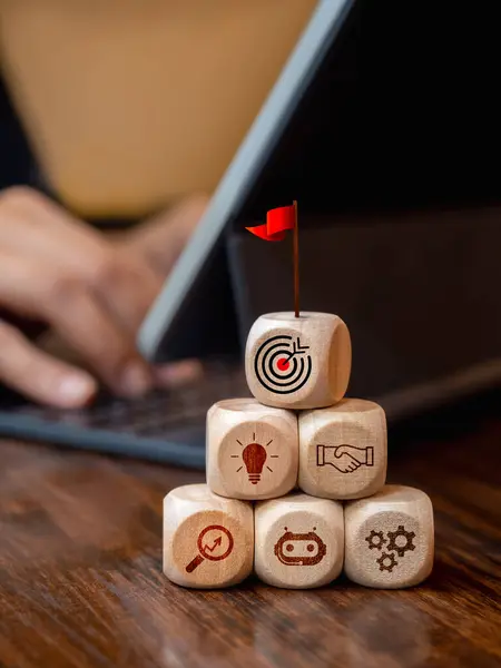 Business growth and success process with AI technology support tools concept. Red flag on the top of wooden cube blocks step with strategy icon while business man working with laptop computer.