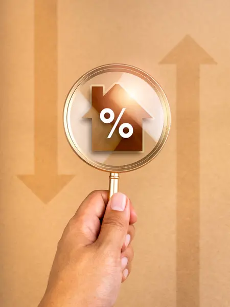 Home tax, interest rates concept. Real estate, land and property annual taxation. Percentage icon on house symbol in magnifying glass lens in hand, brown vertical background with up and down arrows.