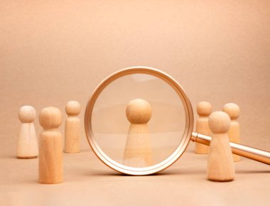İnsan kaynakları (HR), işe alım, seçim, işe alım, CRM, doğru insanlar ve eşsiz kavramlar. Tahta figür insan, kalabalıktan seçilmiş kişi büyüteç içinde bej arka planda..