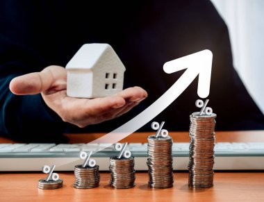 Ev vergisi kavramı, konut veya gayrimenkul vergisi yıllık vergilendirme, satış kavramından kâr. Yükselen ok ve yüzdelik simgesi madeni para yığını grafik adımları ve elinde beyaz küçük bir ev tutan adam.