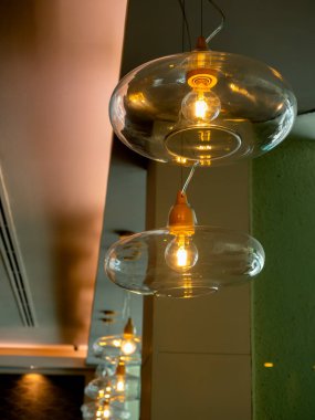 Restoranda ya da kafede tavandan sarkan çok güzel bir retro-lüks lamba. Cam kasenin dikey fotoğrafçılığı modern lüks tasarım kolye lambası parlak odada ampul süslemesi.