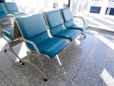 Boş mavi bekleme koltuğu, cam pencerenin yanındaki havaalanı terminali binasında, yolcu, müşteri, turist ve yolcu bekleme salonunda granit döşeme katında 3 koltuk ayarla..