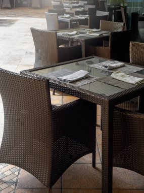 Beyaz keten peçeteler kaşık ve çatalla kaplı tabak paspasları üzerinde boş sandalye koltukları olan masa seti otel, açık alan, dikey stil misafirler için hazırlanıyor..