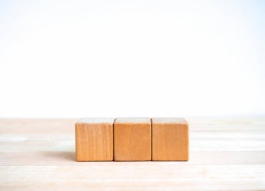 Tahta masada 3 blok izole edilmiş, beyaz afiş arkaplan ve fotokopi alanı. Boş boş şablon metnin için yatay sırada dizilmiş üç küp ya da iş simgesi, eğitim kavramı için simge.