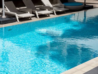 Oteldeki büyük açık yüzme havuzunun yakınındaki misafirler için boş, beyaz, modern bir şezlong sandalyesi. Yaz havuz kenarı görünümü rahatlama arka plan kavramı.