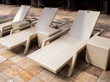 Üç boş modern beyaz rattan güneş yatağı seti, sarı fayanslı yan koltuklar otel havuzunda, açık havuzda konuklara açık havuz, yazlık mobilya konsepti..