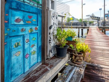 BANDAR SERI BEGAWAN, BRUNEI - 21 Nisan 2024: Bandar Seri Begawan 'ın önde gelen geleneksel yerleşim köyü Kampong Ayer' deki ahşap köprünün mavi kapısında balık resimleri, turizm beldeleri.