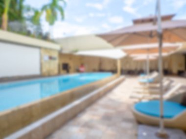 Arka plan ve duvar kâğıdı için oteldeki uzun yüzme havuzu, plaj şemsiyeleri ve güneşlik yataklarının soyut bulanıklığı. Yaz tatilinin bulanık görüntüsü, tatil zamanı konsepti.