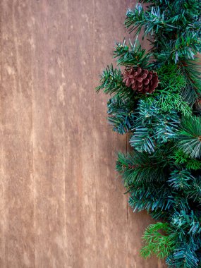 Mutlu Noeller ve mutlu yıllar konsepti. Yakın plan yeşil Noel ağacı, ahşap arka planda çam kozalağı ile süslenmiş. Fotokopi alanı, şenlikli parti süsü, dikey stil..