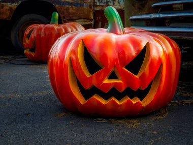 Cadılar Bayramı Jack o Lantern Balkabağı korkunç şeytani yüzlü, açık garajdaki eski model arabanın yakınındaki karanlık zemine yerleştirilmiş. Mutlu Cadılar Bayramı sahne arkası konsepti.