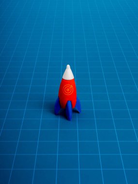 Mavi arka planda izole edilmiş, çevrimiçi ağ şablonlu, minimal tarzda küçük bir oyuncak roket parkı. Yaratıcı yenilik ve fikirler, ilham, eğitim ve öğrenme, ticari başlangıç büyüme kavramı.