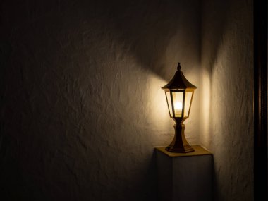Eski siyah post lambası sıcak sarı bir ışık yayar, dekorasyon, fotokopi alanı olan beyaz bir duvarda tek başına durur. Karanlık odanın köşesinde loş ışıklı bir sokak feneri..