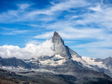 İsviçre Alplerindeki Büyük Matterhorn 'un manzarası. Mavi gökyüzü arka planında beyaz kabarık bulutlu Matterhorn 'un piramitsel zirvesi, İsviçre' de yaz dağları olan turistik bir yer..
