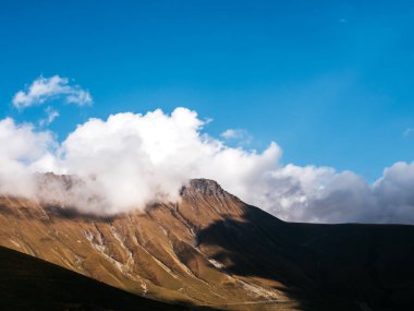 Sonbahar tepeleri arka planda mavi gökyüzünde taş zirvesi güneşli bir günde bulut Juta, Georgia 'da yürüyüş manzarası. Kaya dağının kahverengi ve sarı renkleri, kopyalama alanı olan güzellik manzarası.