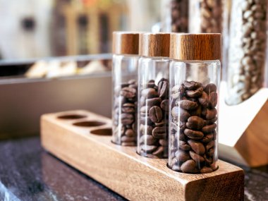 Kafe ya da kafenin arkasındaki tezgah barında küçük ahşap süslemelerde bulunan üç kahve çekirdeği tüpünü kapatın. Kahve konsepti yapmak için gerekli malzemeler.