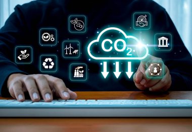 CO2 emisyonları iklim değişikliğini, karbondioksit azaltımını, enerji tasarrufu sürdürülebilir kavramını sınırlıyor. Sanal ekranda iş adamı tarafından işletilen CO2 azaltma simgesi ve alternatif enerji kaynakları.