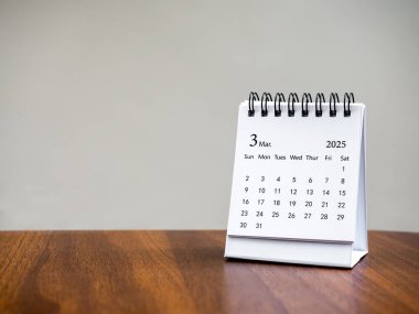 Organizatörün planlaması ve hatırlatması için masa takviminin Mart 2025 sayfası, beyaz zemin üzerinde duran, kopyalama alanı ile ahşap masa üzerinde. Üçüncü aylı küçük masa takvimi, Mutlu yıllar 2025.