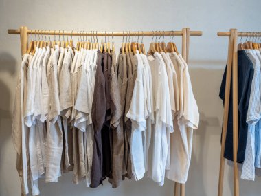 Beyaz, haki rengi, toprak rengi koleksiyonu, askılı askılı gevşek gömlek tarzı ahşap elbise askısı ya da beyaz arka planda elbise askısı..