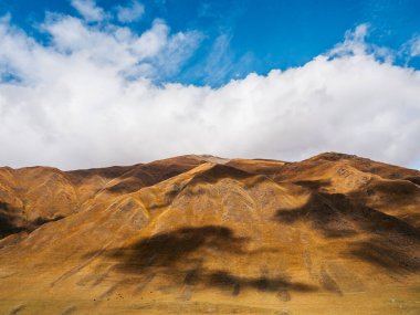 Sonbahar tepelerinde kayalık dağlar mavi gökyüzünde bulutlu arka planda güneşli bir günde Juta, Georgia 'da yürüyüş manzarası. Kahverengi ve sarı renkler küçük dağlarda temiz çimenler, güzellik manzarası.