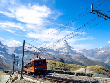 Gornergrat Bahn, Zermatt yakınlarındaki Gornergrat tren istasyonuna giden kırmızı turist treni harika bir manzarası, Matterhorn tepesi, mavi gökyüzü arka planı, ünlü turizm merkezi İsviçre 'de kaybolmaz..