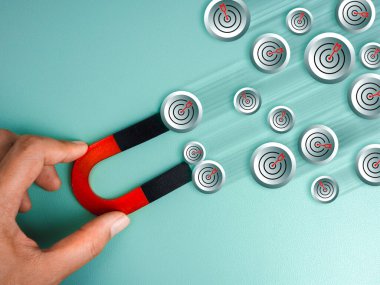 İş dünyası internet dijital pazarlama stratejisi, hedef ve başarı, liderlik vizyonu, müşteri ve müşteri kavramlarını çeker. Hedef dart simgeleri, elinde mıknatıs, mavi arkaplanda izole..