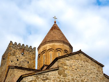 Ananuri Kalesi, kale kulesinde haç, mavi gökyüzü arka planında eski binalar, Gürcistan 'da popüler bir turizm merkezi olan şato kompleksi ile Ananuri köyünün tarihi simgesi..