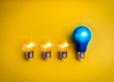 Yapay zeka teknolojisi ve yenilik fikirleri, bireysellik, liderlik, yaratıcı kavramlar. Büyük mavi ampul, küçük açık ampullerden çok parlak, sarı arka planda izole edilmiş, minimalist..