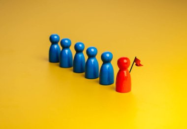 Kırmızı olan, bayraklı, liderli, önde gelen mavi mandal bebekler grubu, takım sembolü, sarı arka planda. Liderlik, menajerlik, benzersiz, nüfuz sahibi, yetenekli insanlar, takım çalışması kavramı.