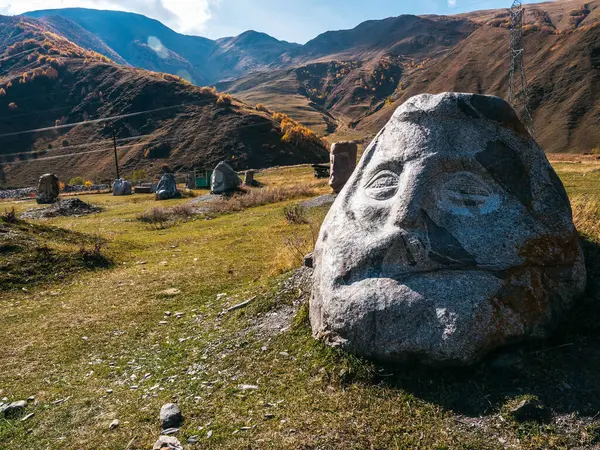 Sonbahar manzarası. Mavi gökyüzü arka planında dağların yakınındaki devasa taş heykeller. Georgia 'da turistik ilgi..