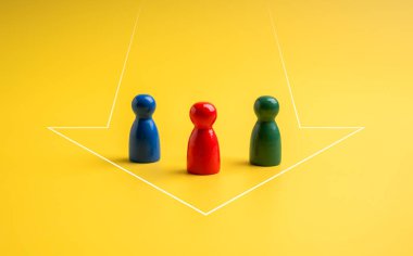 Kırmızı, yeşil ve mavi, mandal bebeklerinin farklı renkleri sarı arkaplanda ok şeklinde bir arada duruyorlar. Liderlik, takım oluşturma, yetenek sahipleri, takım çalışması ve işbirliği kavramları.