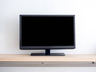 Siyah akıllı televizyonun ön görüntüsü boş, siyah ekran ahşap raf, otel odasındaki beyaz duvar arka planında izole. Dikdörtgen kare uzay ekran LED TV.