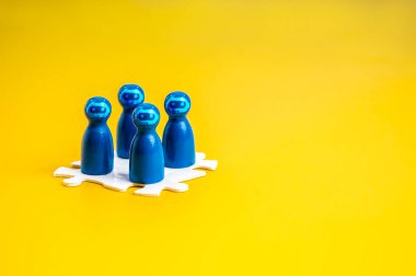 Yapay zeka asistanı, hissedar, iş ve teknoloji, takım çalışması ve takım oluşturma kavramı. Robot yüz ikonuna sahip mavi mandal bebekler, sarı arka planda beyaz yapboz üzerinde yan yana duruyorlar, minimalist..