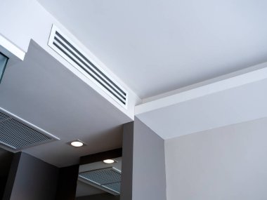 Beyaz, temiz otel odası arka planında tavana monte edilmiş havalandırma sistemi. Otel odasının havalandırma ızgarası duvarda..