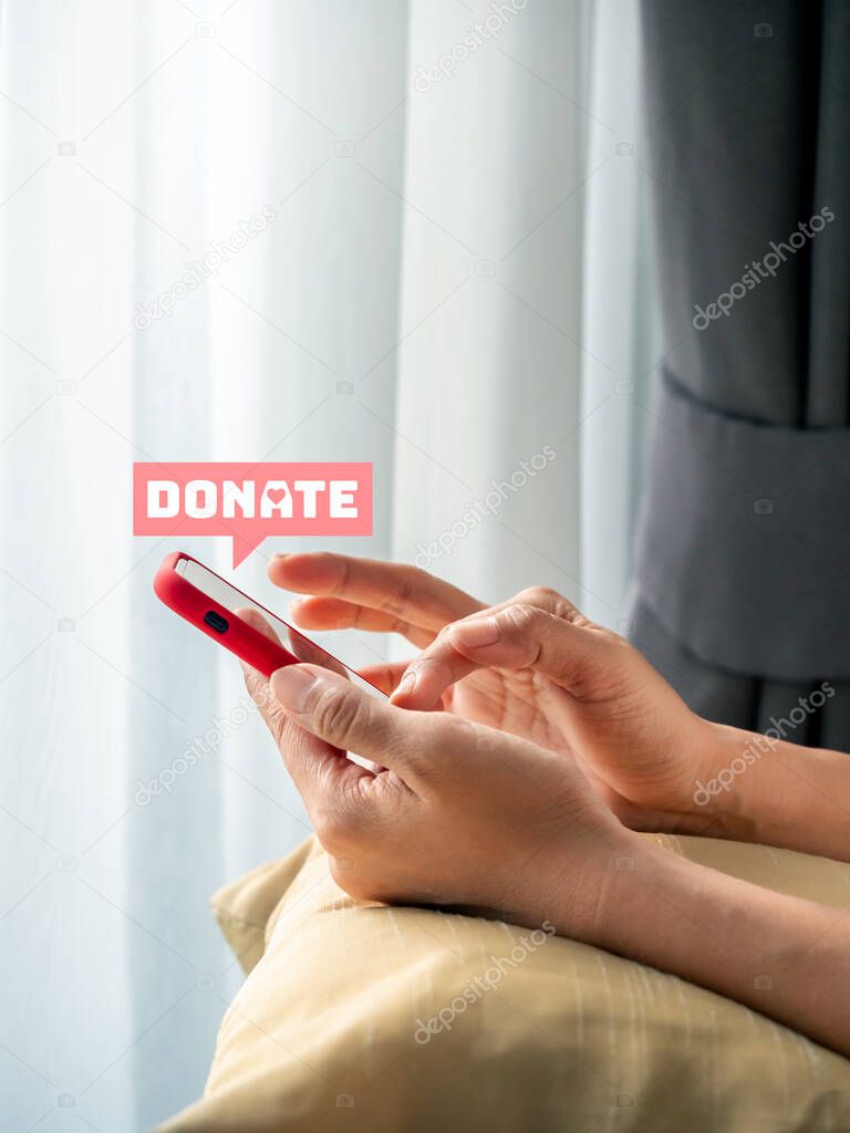 Donate icon in pink bubble speech appear on smart mobile phone in woman's hands, using cellphone while stay in living room, vertical photo. Donation online on application or website concept.