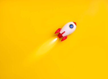 Canlı sarı arka planda uçan yaratıcı roket oyuncağı başlangıç konseptini, yeni proje lansmanını, teknoloji fikrini, yenilik stratejisini, hızlı büyümeyi ve dinamik bir piyasada iş başarısını temsil eder..