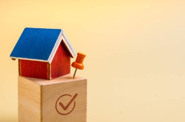 Tahta blokta raptiyeli mini ev modeli ve boşluklu işaret sembolü. Emlak yatırımı, emlak seçimi, konut seçimi, konut piyasası kararı ve mali planlama kavramı.