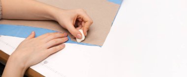 Fotokopi alanı olan bir giysi modeli üzerinde çalışan ellerin yakın çekimi. Moda tasarımı, dersler ve eğitim içeriği için ideal. Tarafsız tonlar ve profesyonel stil.