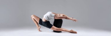 Sanatsal dans pozu. Beyaz ve siyah giymiş bir kadın, gri arka planda. Fitness reklamları, yaşam tarzı promosyonları ya da editörlük kullanımı için mükemmel. Kopya alanı olan geniş pankart..