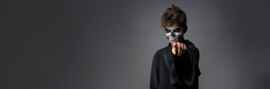 Ürkütücü yüzü olan genç bir adam kamerayı işaret ediyor. Karanlık tonlar ve ürkütücü tarzlar, Cadılar Bayramı terfileri için ideal. Kopyalama alanı olan geniş pankart.