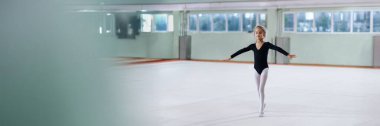 Genç bir balerin geniş bir stüdyoda pratik yapıyor. Yumuşak ışıklandırma pastel renkleri vurgular. Kopya alanı olan dans okulu reklamları için ideal. Geniş pankart biçimi.
