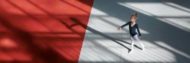 Siyah bir zeminde dans eden genç bir jimnastikçi. Görüntü dramatik gölgeler ve jimnastik veya dans temaları için mükemmel kırmızı ve gri tonların bir karışımını içerir..