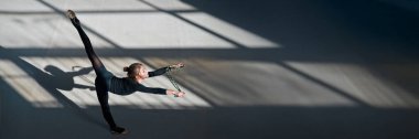 Hareketli genç bir jimnastikçi, kıvrak ve zarif, fotokopi alanı olan geniş bir pankartta. Tarafsız renklere sahip minimalist stil, spor promosyonları veya reklamlar için ideal.