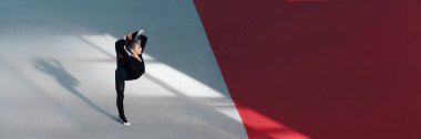 Siyah kıyafetli şık bir jimnastikçi esneme hareketi yapıyor. Minimalist tarz, zıt gölgeler, spor terfileri için uygun. Kopyalama alanı olan geniş pankart.