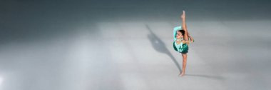 Genç jimnastikçi, deniz mavisi kostümüyle poz veriyor. Havalı tonları olan minimalist bir tarz. Reklamlar, fitness ve spor promosyonları için uygun. Kopyalama alanı olan geniş pankart.