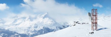 Kırmızı anten kulesi olan karlı dağların manzarası. Parlak mavi gökyüzü ve karla kaplı tepeler. Teknoloji, seyahat ve ticari kullanım için ideal. Geniş pankart.